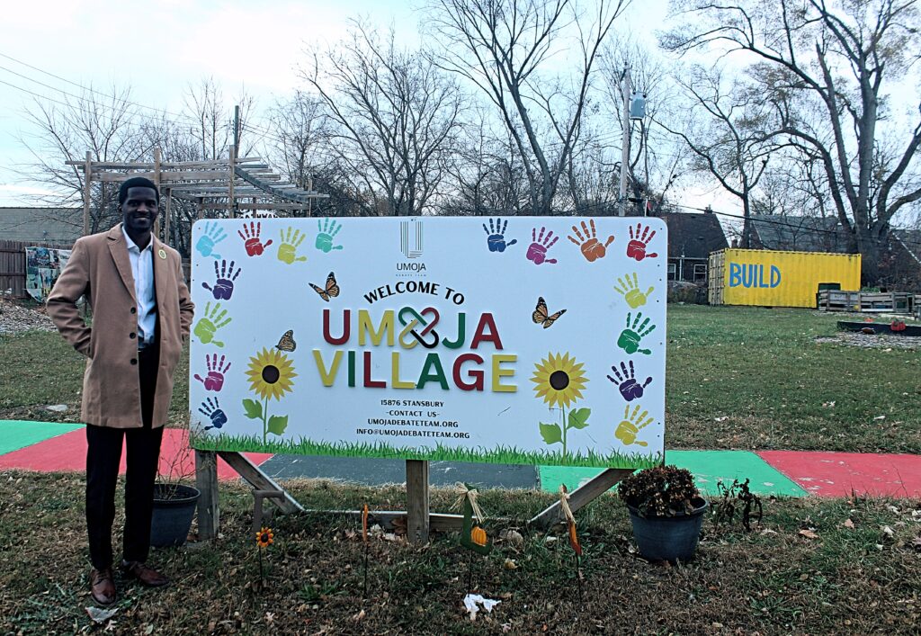 Jerjuan Howard: Community Enhancement Through Literacy Image 6 Handsome black man standing next to a sign in front of a field.
