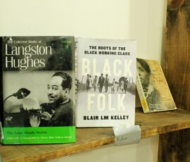 Featured books at Howard Family Bookstore in Detroit. Photo ©2025 by Ryan M Place. All rights reserved. Front covers of "The Collected Works of Langston Hughes", and "Black Folk" by Blair L. M. Kelley on a rustic wooden shelf.