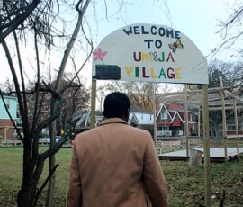 Umoja Community Garden in Detroit. Photo ©2025 by Ryan M Place. All rights reserved. Grassy field with fallen leaves and several wooden structures, leafless trees.
