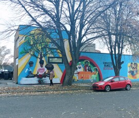 Murals at Howard Family Bookstore in Detroit. Photo ©2025 by Ryan M Place. All rights reserved. Side wall of a 2-story building with several murals painted over a blue background.